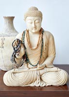 Buddha statuette covered in bead necklaces and bracelets