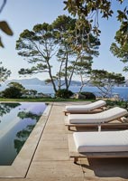Recliners around swimming pool with sea view beyond 