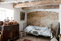 Exposed beams and stone wall in rustic bedroom 