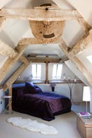 Modern bedroom in converted watermill with exposed beams and mechanisms 