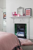 Modern bedroom with fluffy pink rug by fireplace 