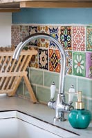 Patterned tiling at back of  sink in country kitchen 