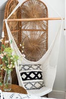 Macrame swing seat and wicker screen in country bedroom 