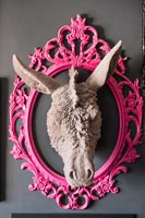 Donkey head sculpture in pink frame on black wall 