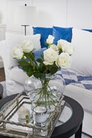 White roses in glass vase on silver tray 