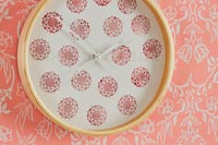Decorative wall clock and colourful orange patterned wallpaper 