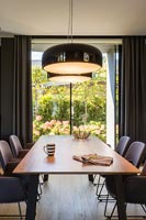Modern dining room with lights on over table 