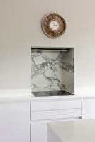 Marble covered alcove over hob with extractor fan and clock 