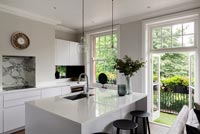 Modern monochrome kitchen with open French windows to balcony 