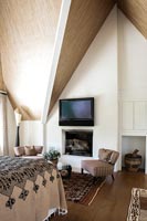 Television above fireplace in country bedroom 