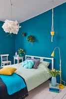Modern bedroom with blue painted walls and spring flowers at Easter 