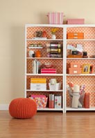White bookcases backed with orange wallpaper