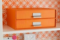 Orange cardboard filing drawers on bookcase shelf 