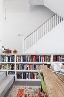 Staircase in modern dining room with bookcase built around steps 