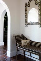 Striped recliner and ornate mirror in country hallway 