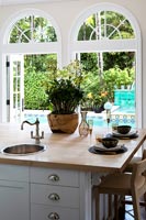Wooden kitchen island with view through window to swimming pool 