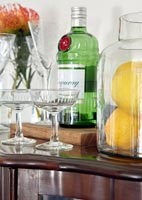 Gin, lemons and glasses on sideboard 