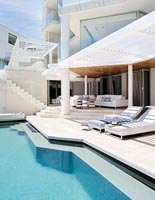 Contemporary house exterior with swimming pool and recliners 