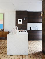 Modern kitchen with marble island and brick tiles on floor 