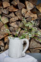 Wood pile and jug with flowers 