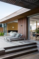 Recliners on raised deck outside contemporary house 