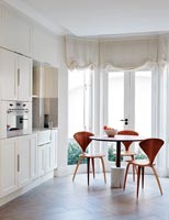 Cream kitchen with small circular dining table and chairs 