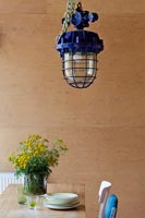 Industrial lamp and flowers in front of plywood wall