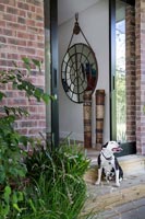 Pet dog sitting on doorstep of modern house with view through front door 