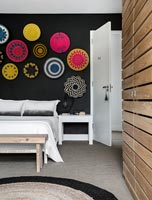 Modern bedroom with display of decorative wicker plates on black wall 
