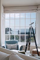 Telescope next to window with sea view 