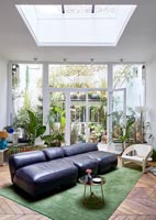 Leather divan sofa in modern living room with view to courtyard garden