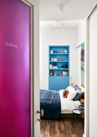 Pink door with 'nothing' written on it and view into modern bedroom 