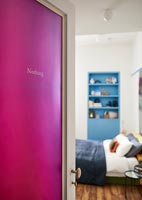 Pink door with the word nothing written on it and view into modern bedroom 