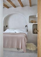 Country bedroom with moulded arch alcove at head of bed 