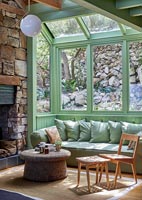 Country living room with stone walls and green painted window frames 