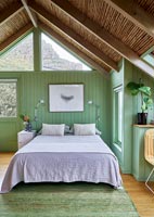 Country bedroom with green painted wooden walls 