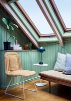 Chair in corner of room with large skylight windows and painted wooden walls 