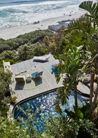 Overhead view of swimming pool and decked outdoor living area by sea 