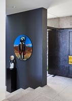 Colourful artwork on black painted wall in contemporary hallway 