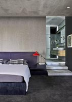 Contemporary bedroom with concrete ceiling and view into en-suite bathroom 