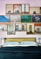Display of framed photographs over bed in modern bedroom 