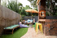 Colourful furniture in garden with brick barbecue area 