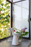 Cut flower arrangement in glass jar on windowsill