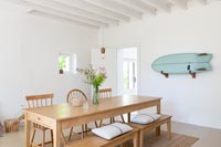 Wall mounted surfboard in white country dining room with wooden furniture 