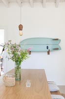 Blue wall mounted surfboard on white country dining room wall 