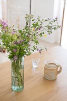 Detail of wildflower arrangement in vase on wooden table 