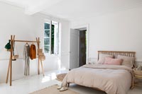 White country bedroom with simple wooden clothes rail 