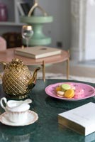Golden teapot and cakes on coffee table 