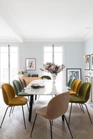Different coloured upholstered chairs around vintage marble dining table 