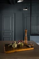Artichokes on chopping board in kitchen with dark grey painted walls 
